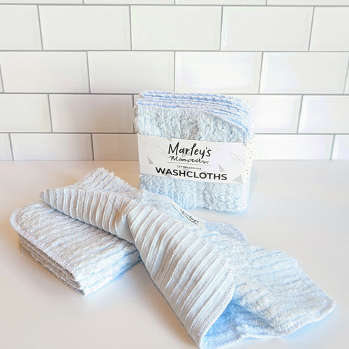 100% sky blue-colored cotton chenille washcloths on a white and subway tile background.