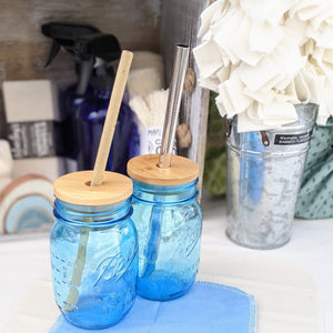 Two blue mason jars with bamboo hole-top lids. One with a bamboo straw, one with a metal boba straw.